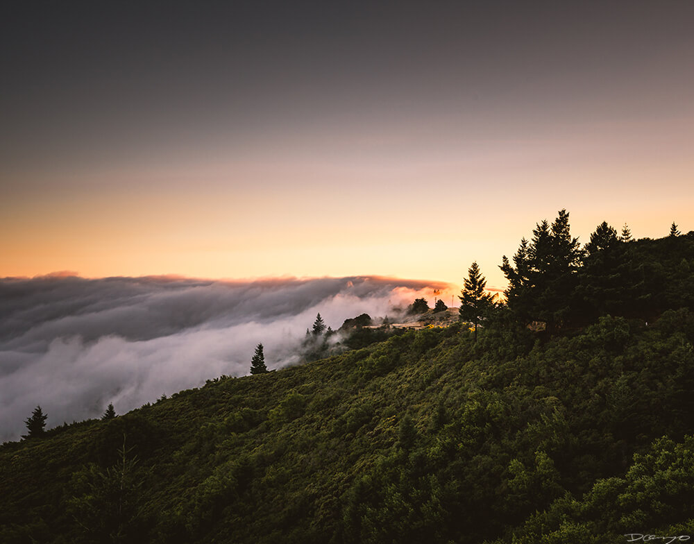 Bright orange and pink sunset with fog rolling over Mount Tam, CA