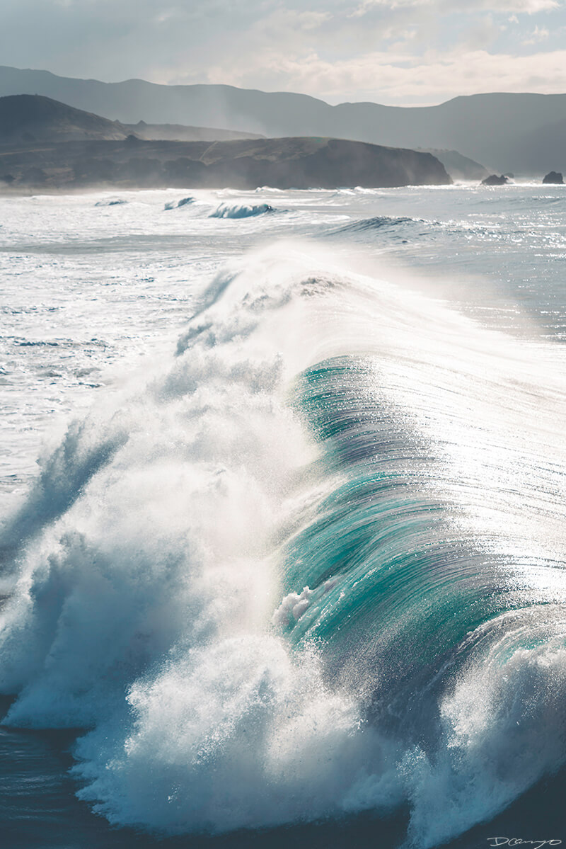 A large wave seen from above breaking and crashing under the Pacifica Pier in Pacifica, CA
